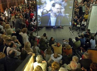 Asistentes al mitin del PP en Pamplona siguen la intervención de Mariano Rajoy en el Palacio de Congresos a través de pantallas.