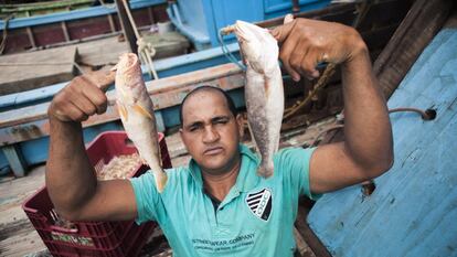 O pescador Cristiano Marques dos Santos, apelidado de Hulk, posa para a foto mostrando alguns dos peixes pescados no mar. 