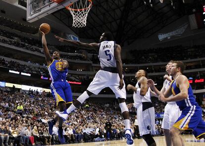 Harrison Barnes, de los Golden State Warriors, lanza ante el pívot de los Mavericks, Bernard James.