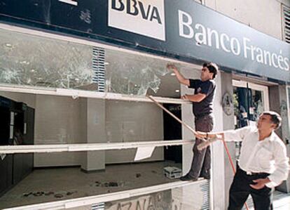 Trabajadores del BBVA Banco Francés de Buenos Aires arreglan los desperfectos provocados por la revuelta del viernes por la noche.