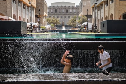 Un niño y su hermana se bañan en una fuente de la Plaza Tapatía en Guadalajara durante la ola de calor de mayo de 2024.