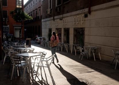 Una joven pasa entre la terraza vacía en la Sidrería La Cuenca, en el centro de Madrid, el viernes por la tarde.