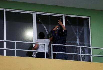 Una pareja en el momento de proteger las ventanas de su casa ante la llegada del huracán Willa, en Mazatlán.