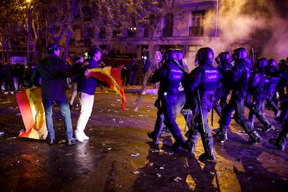 Un manifestante, bandera de España en mano, se encara con los antidisturbios en las cercanías de la calle de Ferraz, este martes. 