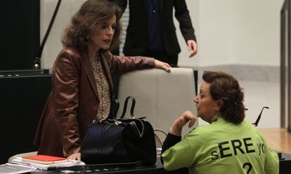 Durante el pleno municipal, varios concejales de IU se han vestido con una camiseta para protestar por los despidos en la empresa municipal Madridec. En la imagen, Milagros Hernández habla con la alcaldesa.