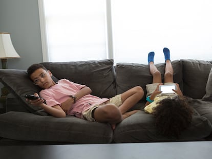 Dos niños aburridos en el sillón de su casa.