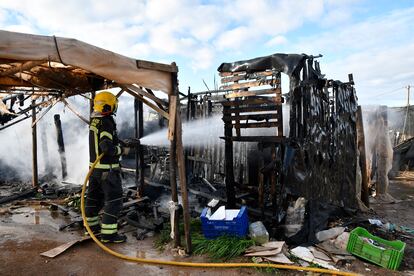 Un bombero apaga el fuego de una chabola incendiada durante el desalojo del campamento "El Walili" en Níjar (Almería).