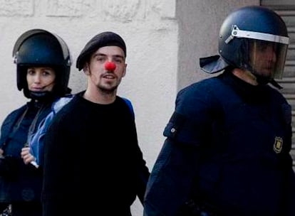 Uno de los jóvenes ocupantes de Can Ricart abandona el recinto fabril, ayer, acompañado por un <i>mosso d'esquadra.</i>