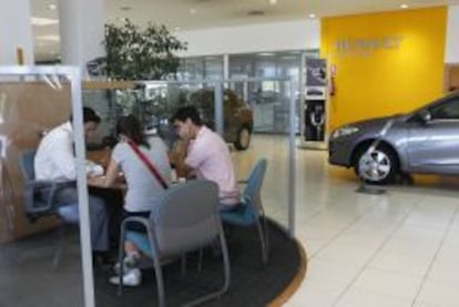 Unos clientes son atendidos por un trabajador en un concesionario de Renault.