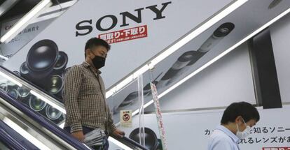 Dos personas pasan junto a una publicidad de Sony en una tienda en Tokio. 