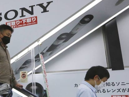 Dos personas pasan junto a una publicidad de Sony en una tienda en Tokio. 