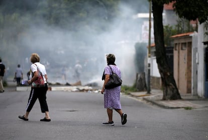 Dos mujeres pasan junto a una barricada levantada por los opositores al gobierno de Nicolás Maduro durante una manifestación en contra del gobierno venezolano en Caracas (Venezuela).