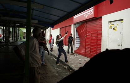 Uma policial civil aponta uma arma para saqueadores de lojas que aproveitaram a greve dos policiais militares em Pernambuco.