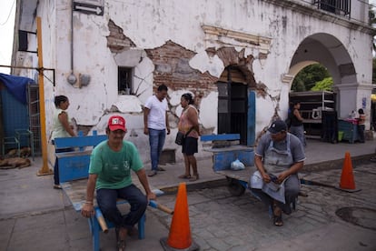 Dos trabajadores esperan pedidos al lado del palacio municipal (antigua sede del Ayuntamiento), abandonado tras los graves destrozos sufridos por el terremoto del 7 de septiembre de 2017.