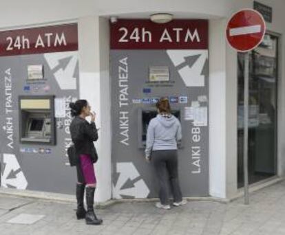 Dos mujeres sacan dinero la pasada semana de un cajero de una sucursal cerrada del Banco de Laiki, en Nicosia.