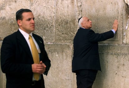 7 de fevereiro de 2001. Um guarda-costas protege o primeiro-ministro eleito Ariel Sharon que toca o Muro das Lamentações enquanto reza, no dia após ter vencido as eleições legislativas israelenses.