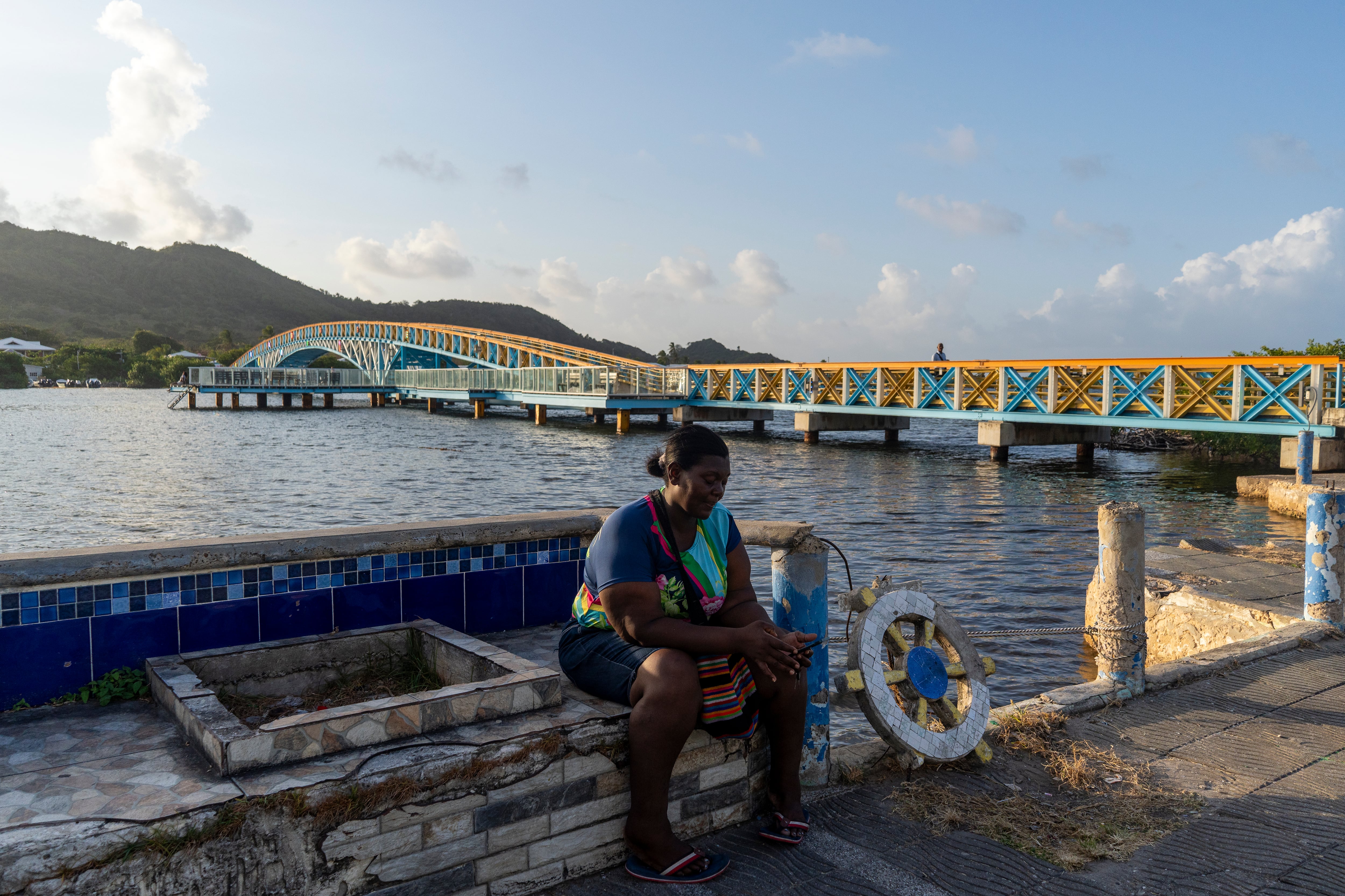Una mujer descansa frente al mar con el puente que conecta Providencia y Santa Catalina.