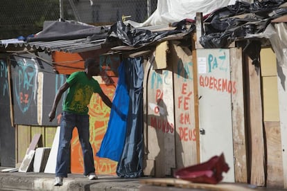 Alguns barracos têm portas e frases pintadas como "Queremos paz"e "Paz e fé em Deus". Outros, têm sua privacidade garantida com pedaços de tecido pendurados, como este onde o homem está entrando.