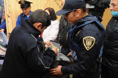 Los policías revisan las mochilas de los estudiantes en una escuela de México.