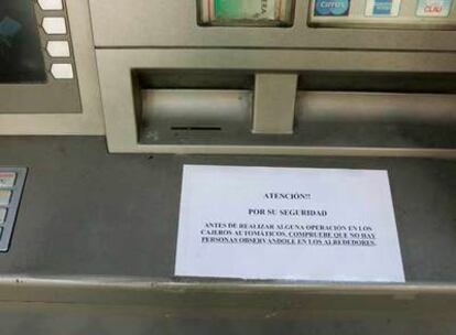Un cartel alerta a quienes vayan a sacar dinero del cajero de un banco en la calla de Ríos Rosas.