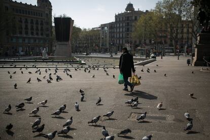 Una hombre camina cargado con la compra por la plaza Catalunya de Barcelona, el 19 de marzo.