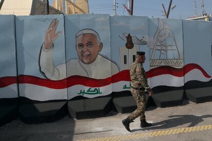 Un miembro de las fuerzas armadas iraquíes pasa junto a un mural que representa al papa Francisco, en un muro de hormigón colocado por las fuerzas de seguridad iraquíes para rodear la Iglesia de Nuestra Señora de la Salvación durante los preparativos para la visita del Papa, en Bagdad (Irak).