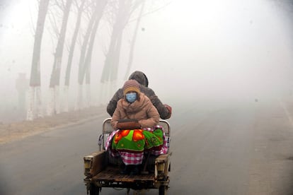 Los altos niveles de polución en el norte de China se han vuelto cada vez más comunes debido a la producción de la industria en la zona, especialmente durante el invierno. En la imagen, una mujer sentada en el remolque de una motocicleta entre la niebla tóxica, en Liaocheng (China).