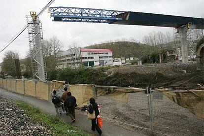 Varias personas contemplan el avance en el aire del tablero del puente hacia el pilar.