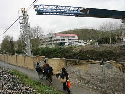 Varias personas contemplan el avance en el aire del tablero del puente hacia el pilar.