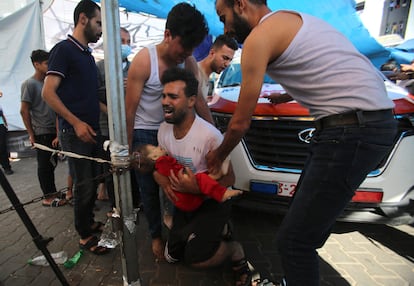 Un hombre llora mientras sujeta a un bebé en la entrada del hospital Al Shifa tras un bombardeo en el barrio de Mansura, este sábado en Gaza. 