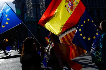 Varias personas sujetan banderas de la Unión Europea, de España y Cataluña, durante la manifestación celebrada en Madrid.  