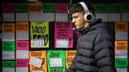 Un joven pasa frente a una carnicería con precios a la vista, en Buenos Argentina, Argentina, en 2024.