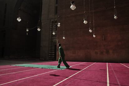 Un trabajador limpia alfombras en la mezquita-madrasa del Sultán Hassan en El Cairo, Egipto.