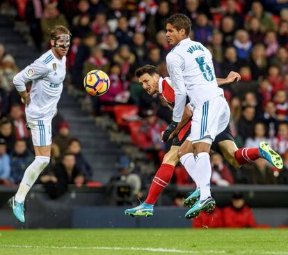 Aritz Aduriz golpea el balón con la cabeza anted Sergio Ramos y Varane.