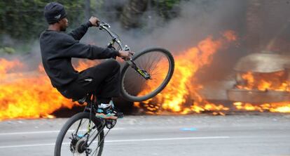 Un joven hace acrobacias ante coches ardiendo en Baltimore.