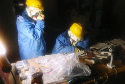 Dos trabajadores de la empresa Tepco trabajan en el interior de la central de Fukushima a oscuras y equipados con los trajes contra la radiactividad.