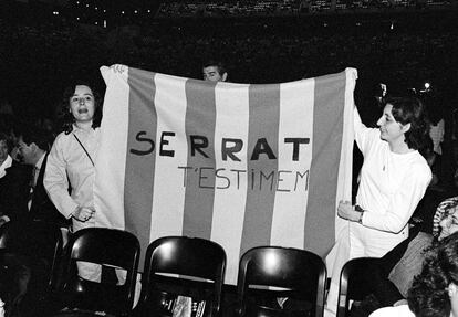 Dos asistentes al concierto de Serrat en el Palau Sant Jordi sujetan una pancarta con un lema alusivo al cantautor.