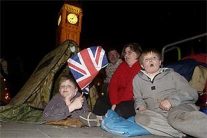 Una familia pasa la noche en la calle en espera del paso del cortejo fúnebre de la reina madre