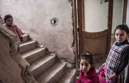 Três meninas brincam na porta de sua casa em um prédio parcialmente destruído pelos bombardeios em Raqa.