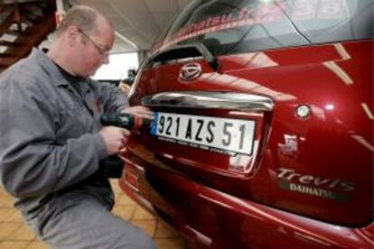 Un experto coloca una placa nueva en un coche. EFE/Archivo