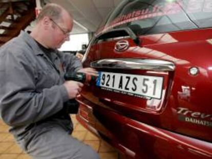 Un experto coloca una placa nueva en un coche. EFE/Archivo