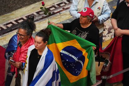 Una mujer con una bandera brasileña se forma para rendir homenaje a José Mujica.