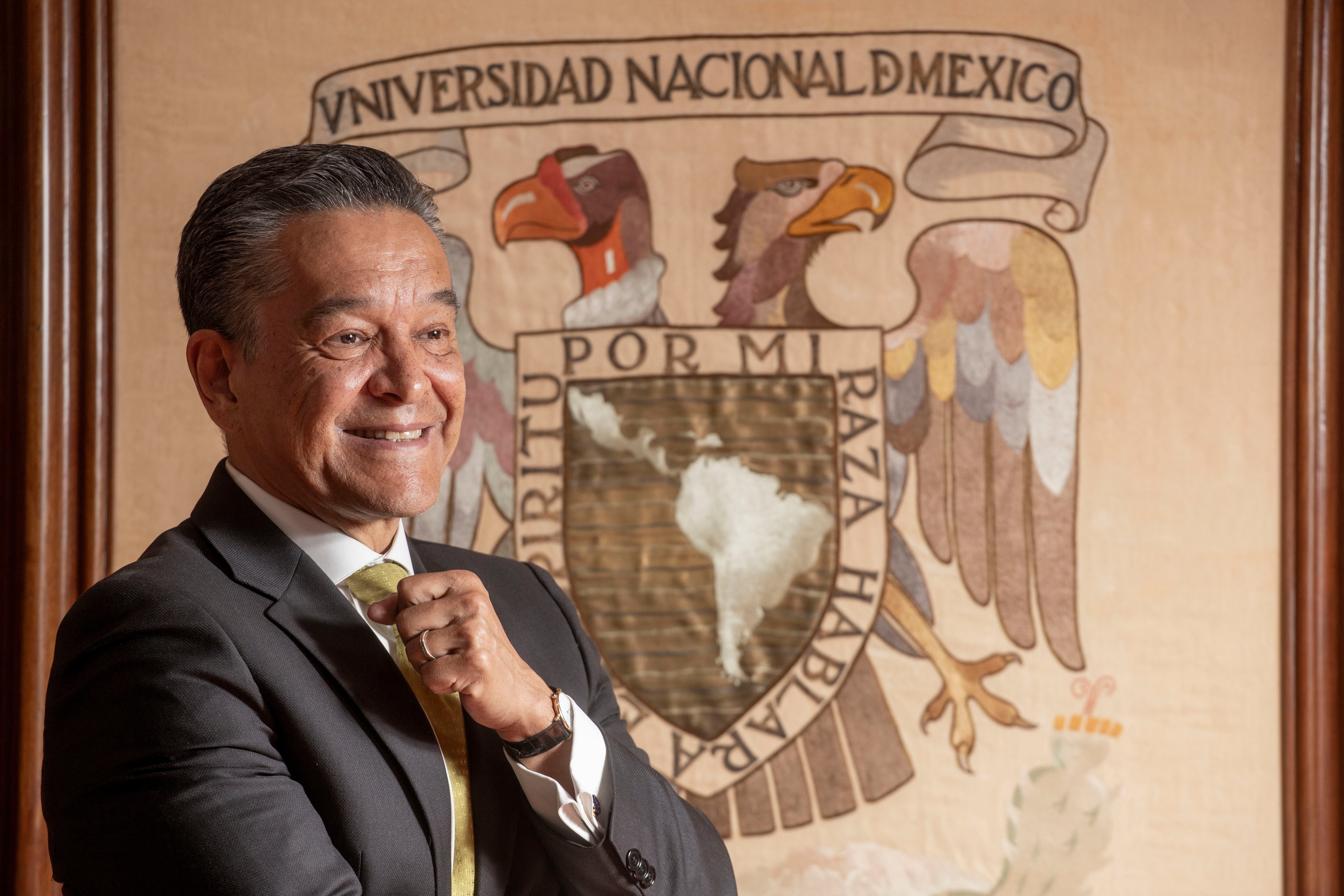 Raúl Contreras Bustamante, junto al escudo de la Universidad Nacional Autónoma de México, en su oficina en Ciudad Universitaria.