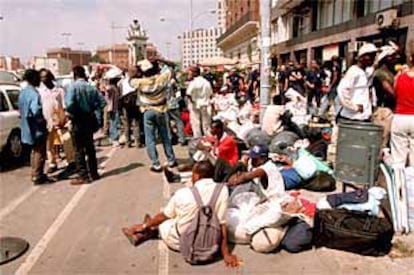 Los inmigrantes desalojados de la plaza de Cataluña se concentran frente a unas dependencias del ayuntamiento de Barcelona.