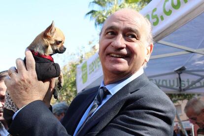 El candidato del PPC por Barcelona, Jorge Fernández Díaz, bromea con una perrita al finalizar su visita al mercado semanal de Can Vidalet, en Esplugues de Llobregat.