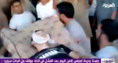Fotograma tomado del canal de televisión Al Arabiya de varios manifestantes mientras evacúan a un hombre herido tras los ataques del ejército en Hama (Siria).