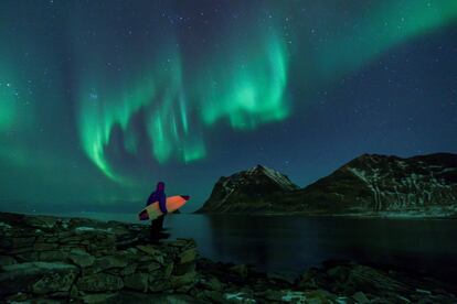 
Un surfero admira una aurora boreal en Utakleiv, más allá del círculo polar ártico, en las Islas Lofoten (Noruega).