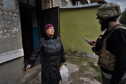 El voluntario Anton entrega una bolsa con comida a Ludmila, de 81 años, que vive sola en su apartamento de Kupiansk. 