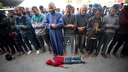 Varios hombres rezaban ayer ante el cadáver de un niño en Deir al-Balah (Gaza)