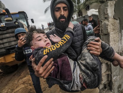 Un hombre lleva a un niño herido y rescatado debajo de los escombros de su casa familiar, destruida tras un ataque aéreo israelí contra Deir Al Balah, en el sur de la Franja de Gaza.